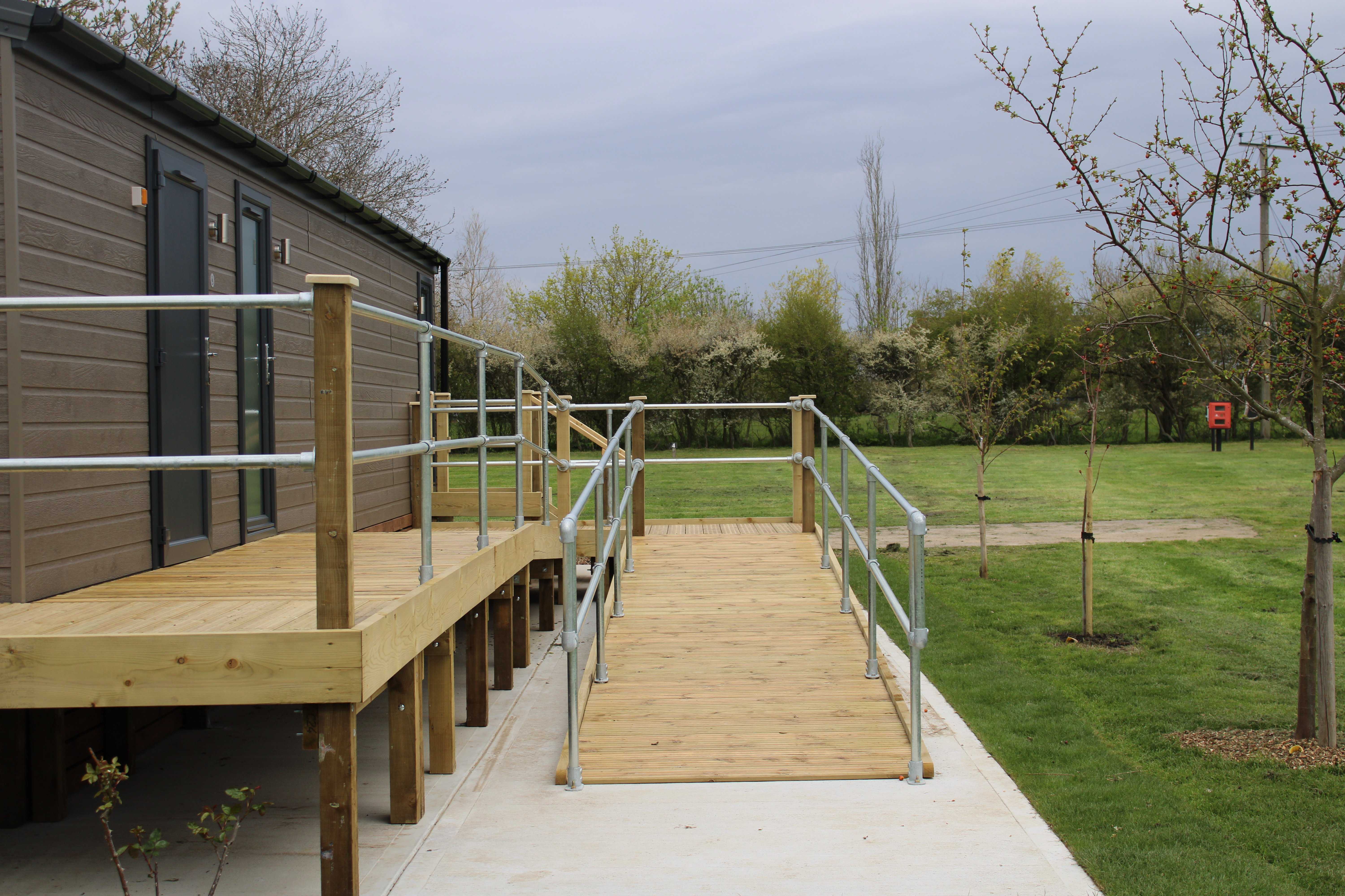 Image of the entrance to a wheelchair access ramp leading to a cabin with toilets and washing facilities