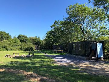 A view of the camping field including the campsite kitchen and communal firepit.