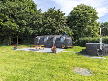 The cabin in a private garden with outdoor seating and a hot tub