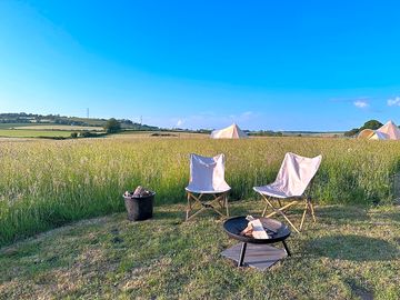 Furnished bell tents have a fire oit ab outdoor chairs