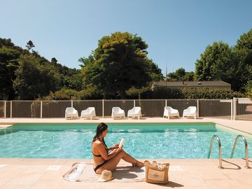 Vacancière lisant un livre au bord de la piscine de notre camping val fleuri © léa tavolaro