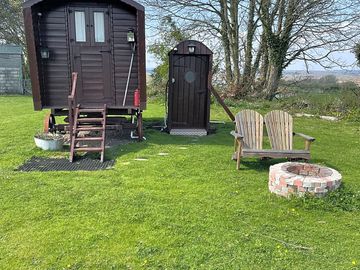 Outside shepherds hut showing the toilet block and seating with fire pit