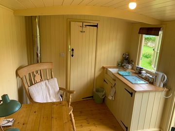 Shepherd's hut kitchen with a mini fridge, microwave, hob kettle toaster and utensils