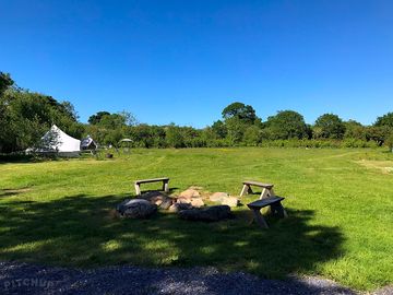 A view up the camping field with the communal firepit in the foreground.