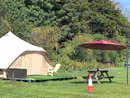 Shaded picnic bench by each bell tent