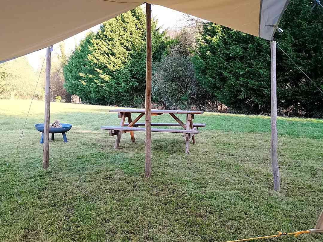 Wye Tipi Camping: View from bell tent door, showing canvas shelter, picnic bench and firepit