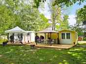 Outside view of the cabin with decking, fire pit, gazebo, seating and kitchen area