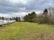 Looking down the motorhome pitches, between the trailers and the road behind the trees