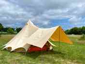 Bell tent in a hay meadow; among establishing nut trees.