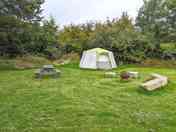 Octagonal tent with outdoor seating and firepit