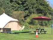 Shaded picnic bench by each bell tent