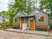 Outside of luxury pod with TV , fridge, kettle, couch, microwave