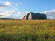 Pods set in a peaceful meadow with mountain and sea views
