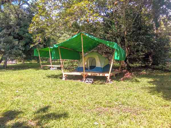 Staplaats voor een tent op gras en aarde zonder elektriciteit (in de schaduw)