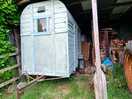 View of classic wooden trailer and an old tractor on campsite.