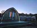 The pod and hot tub at night with lights.