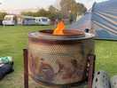 Repurposed washing machine drum fire pit available for use.