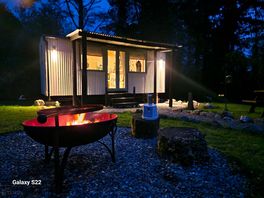 Evening setting of hut and fire pit.