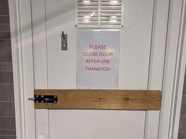 Door secured with wooden batten and single lock due to damage.