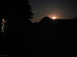 Campsite field darkness with reddish moon.