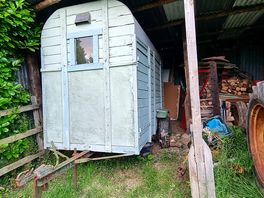 View of classic wooden trailer and an old tractor on campsite.