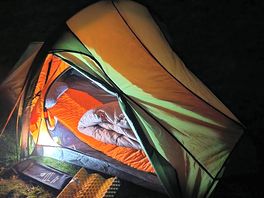 Pitched tent during the night, with the entrance of it open.