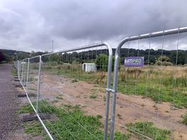 Construction fencing separating campground from wasteland alongside