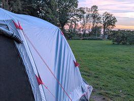 Tent on camp site with sunset in background