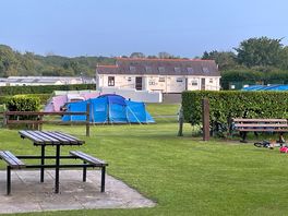 Tents pitched on grass pitches filed with shower block in the background.