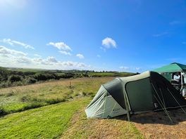 A view of the campsite with the tent in front and the field behind
