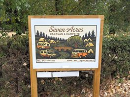 Signpost at the entrance of campsite showing campers and weeping willows and birch trees