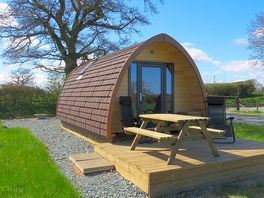 Rainbow View glamping pod with picnic table and deck chairs.