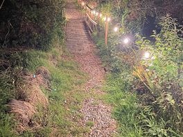 Magical path to the sea, beautifully lit at night — peaceful and full of charm.