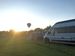 Evening with hot air balloons overhead.