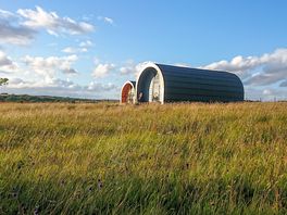 Pods set in a peaceful meadow with mountain and sea views