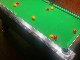 Pool table in back room with a dart board and fruit machine