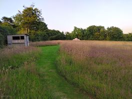 Photo of tent nestled in nature well mown paths link the camping spots.