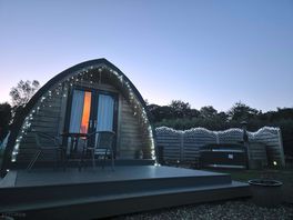 The pod and hot tub at night with lights.
