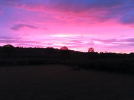 Sunrise over fields and hills.