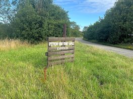 The sign post for the campsite at the road edge