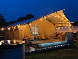 Our deluxe camping tent with hot tub at night.