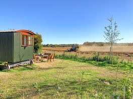 The Sussex Hut with the combine harvester doing its thing in the field
