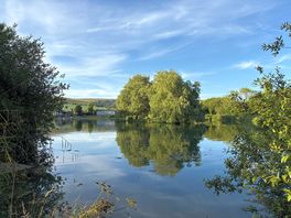 Photo of the lake from the south end looking towards the island, with hills in the background.