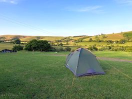 A solo tent looking out over a green hilly landscape