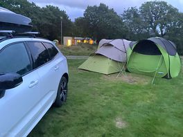 Electric hook up pitch with facilities in the background.