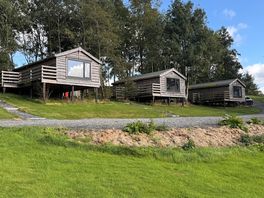 Cosy cabins set on a peaceful green hillside, perfect for a relaxing countryside getaway.