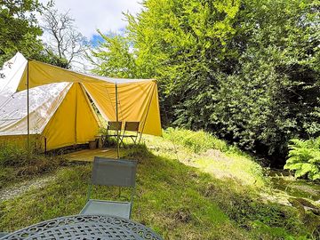 Bell tent exterior, stream and bbq table