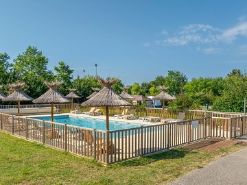 Fenced-off pool with umbrellas and sun loungers