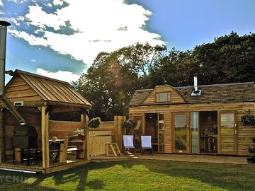 View from the front shows private hot tub and wooden veranda with barbecue