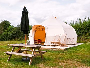 Picnic bench and parasol with each bell tent. photo taken by boutique camping.